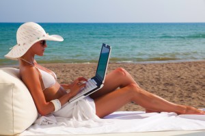 woman on beach working on  laptop against the sea